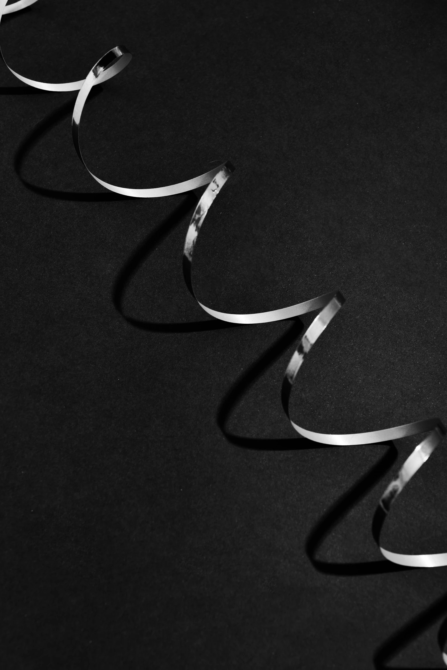 a group of scissors that are next to each other, a black and white photo, by Peter Churcher, minimalism, ribbon, swirles, platinum jewellery, detailed product image