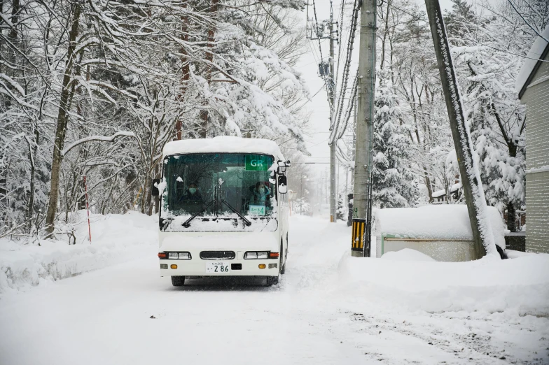 a white bus driving down a snow covered street, shin hanga, fan favorite, grey, maintenance photo, getty images