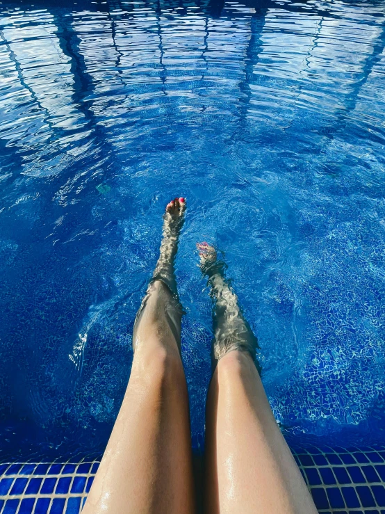 a close up of a person's legs in a pool, by Julia Pishtar, pexels contest winner, renaissance, transparent skin, clear blue water, barefeet, holiday season