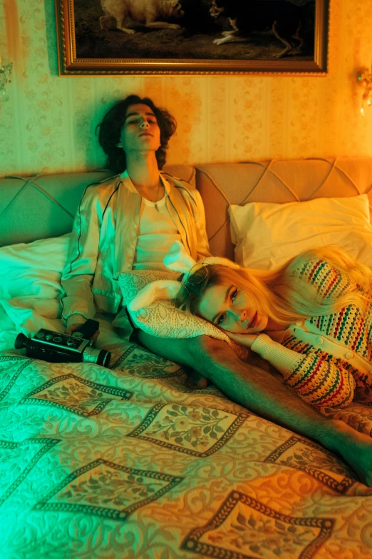 a couple of women laying on top of a bed, an album cover, inspired by Nan Goldin, trending on pexels, renaissance, robert sheehan, in full technicolor, perfectly lit. movie still, bright scene