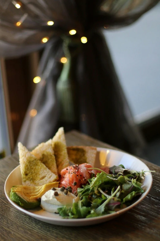 a plate of food sitting on top of a wooden table, a still life, daily specials, salad, lights on, ivy's