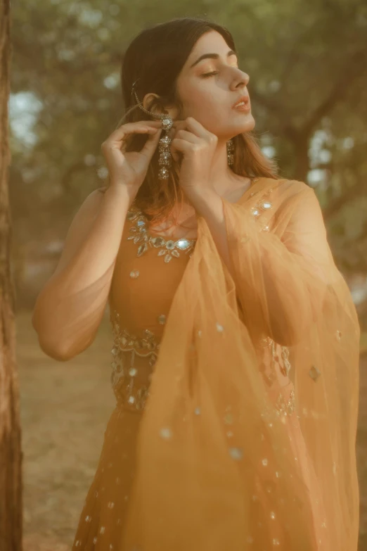 a woman in a yellow dress standing next to a tree, inspired by Saurabh Jethani, trending on pexels, renaissance, covered in jewels, ochre, asian woman, finer details : 3