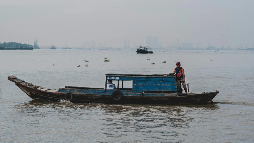 a man standing on top of a boat in the water, by Joseph Severn, pexels contest winner, river delta, city in the background, mai anh tran, banner