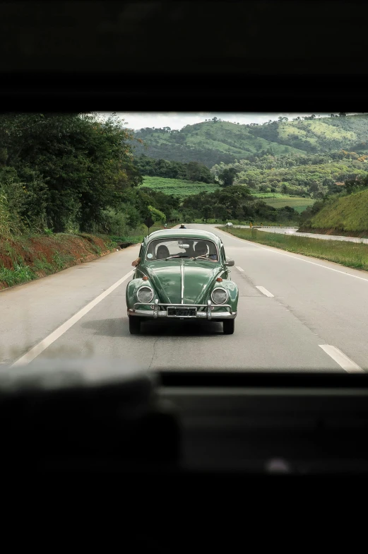 a car that is sitting on the side of the road, by Ceferí Olivé, pexels contest winner, renaissance, beetle, road between hills, 1960s color photograph, a green