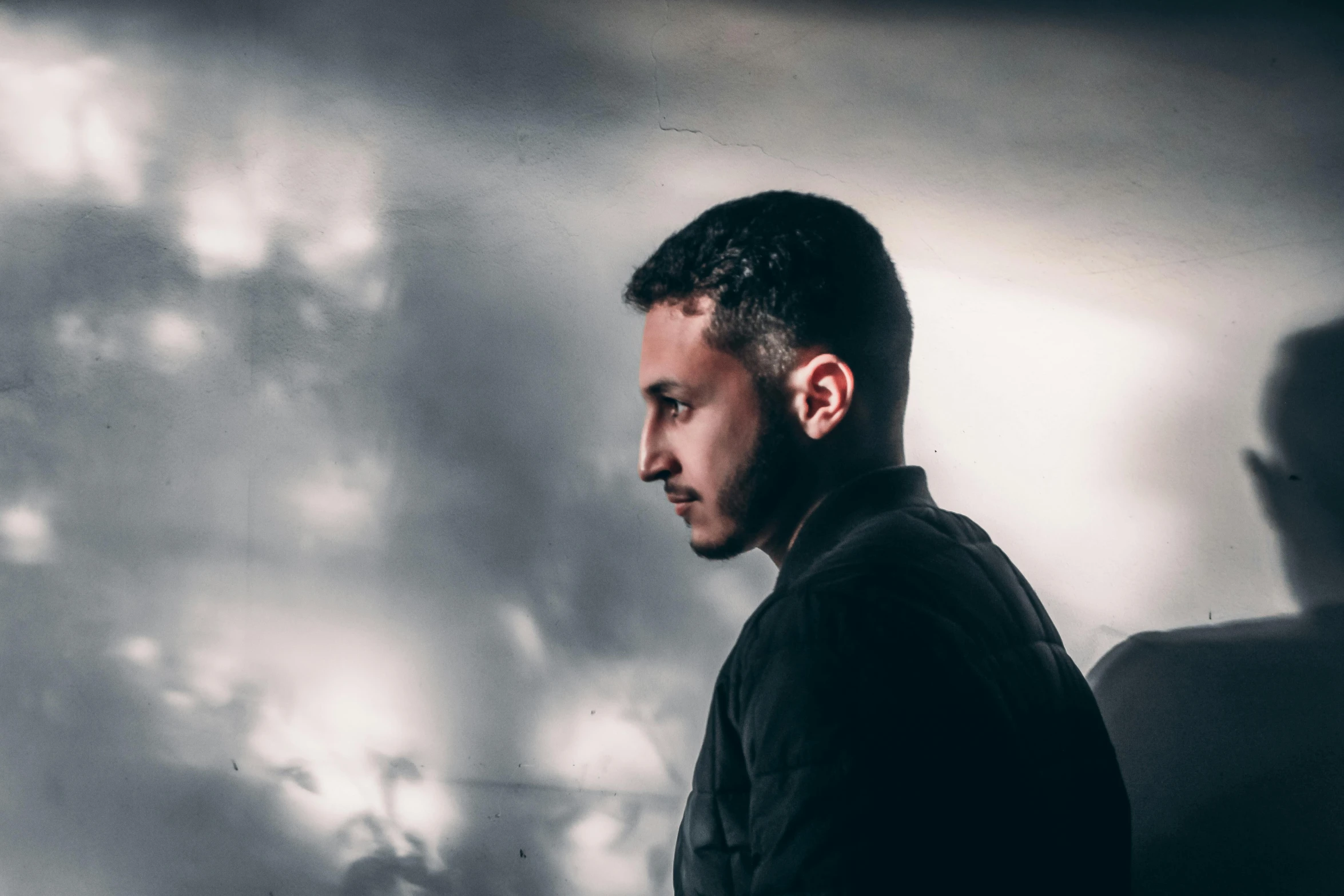 a man sitting in front of a laptop computer, an album cover, pexels contest winner, hurufiyya, profile portrait, shadowy lighting, background image, haze over the shoulder shot