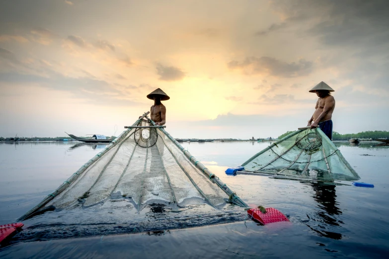 a couple of men standing on top of a body of water, a picture, nets and boats, bali, featured art, fish lens