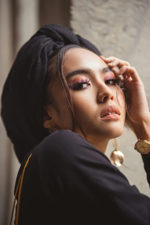 a woman leaning against a wall with her hand on her head, an album cover, by Basuki Abdullah, trending on pexels, hurufiyya, black eyeshadow, square, lips, vietnamese woman