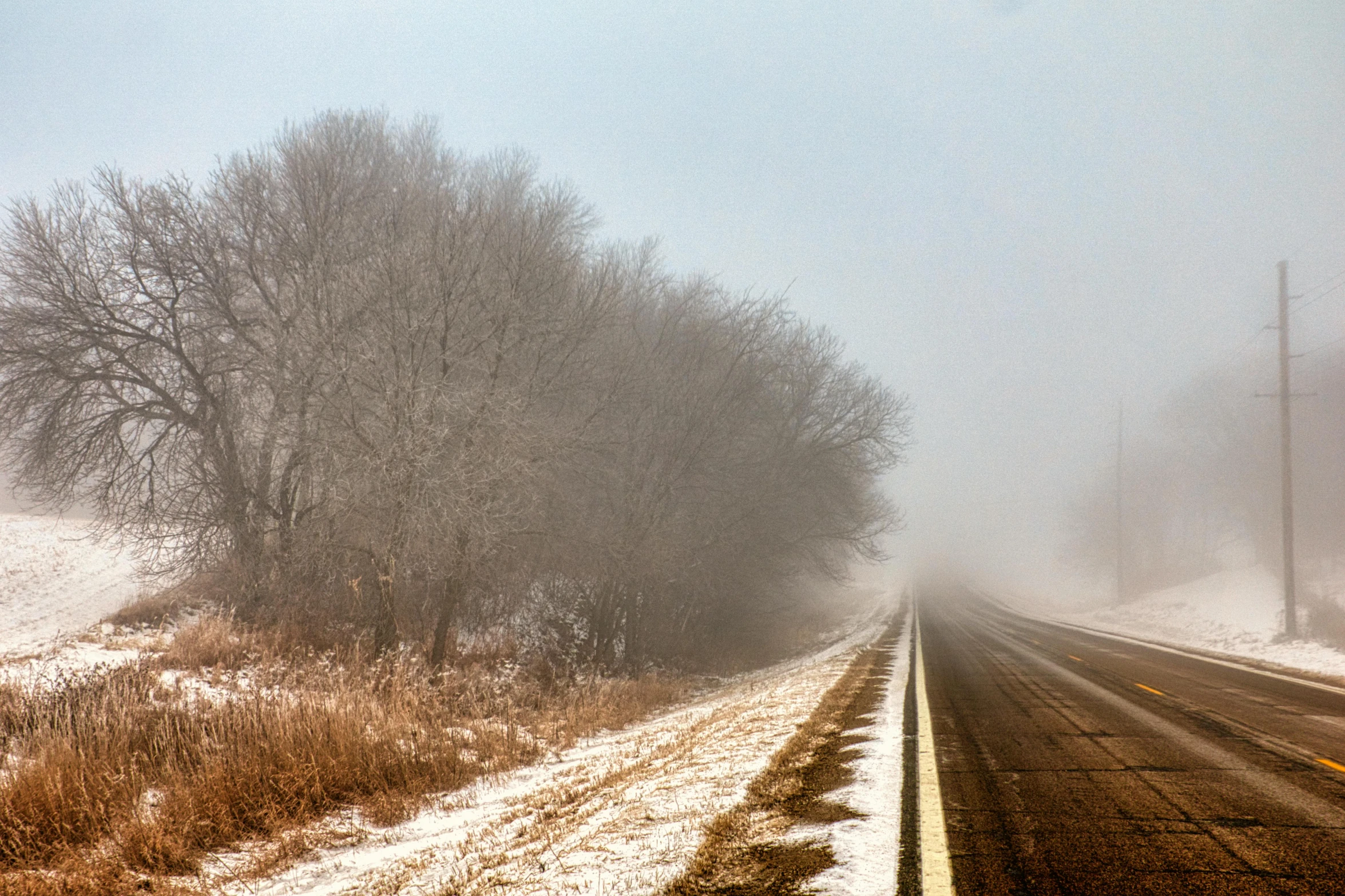 a road in the middle of a field covered in snow, by Robert Storm Petersen, pexels contest winner, low angle mist, old american midwest, ((mist)), brown mist