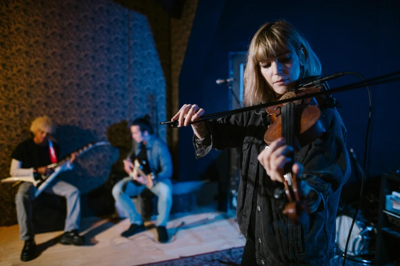 a woman playing a violin in a music studio, an album cover, unsplash, realism, trio, blue grass, performing on stage, carson ellis