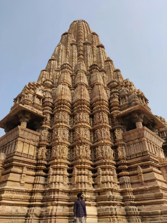 a man standing in front of a tall building, epic khajuraho, closeup!!!!!, castles and temple details, front facing!!