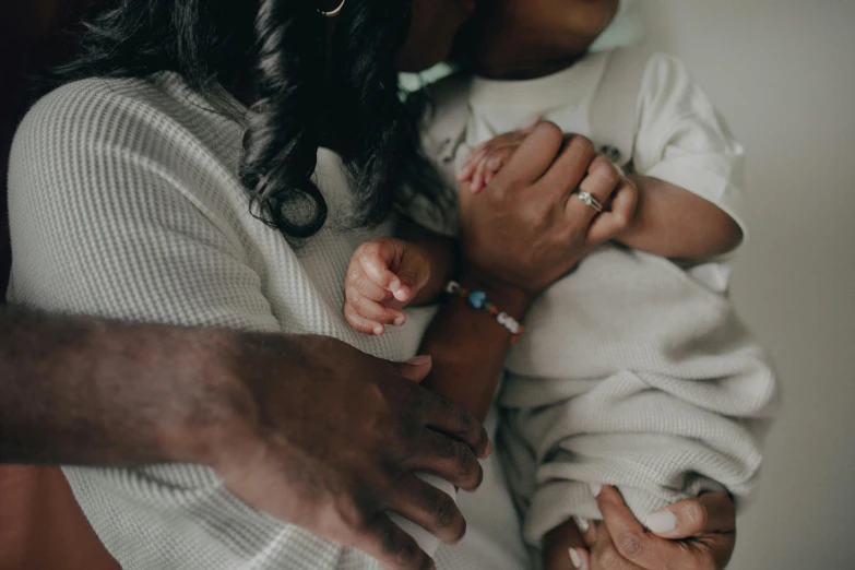 a woman holding a baby in her arms, pexels, 3 - piece, dark-skinned, holding hand, laying down