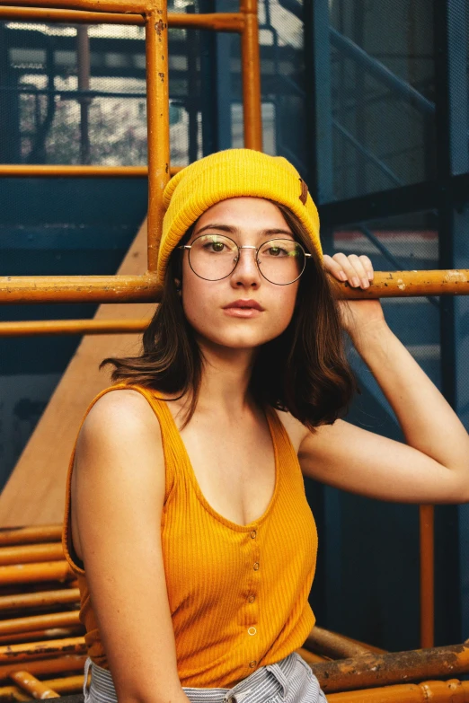 a woman wearing a yellow hat and glasses, inspired by Elsa Bleda, trending on pexels, handsome girl, square glasses, grungy, casual pose