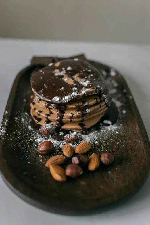 a stack of pancakes sitting on top of a wooden plate, a still life, trending on pexels, dark chocolate painting, nut, thumbnail, 8