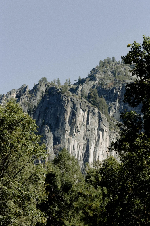 a mountain in the distance with trees in the foreground, steep cliffs, granite, exterior, napa