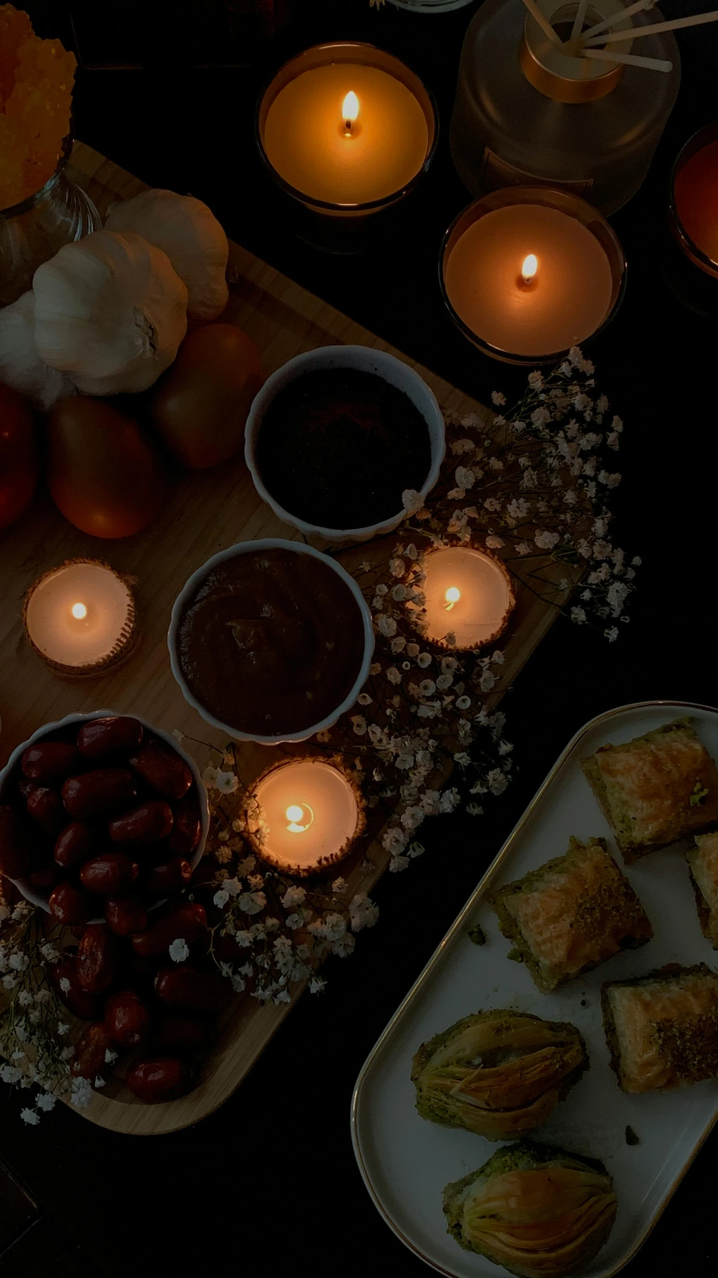 a table topped with plates of food and candles, inspired by Elsa Bleda, pexels, hurufiyya, dark grey, square, low quality photo, brown