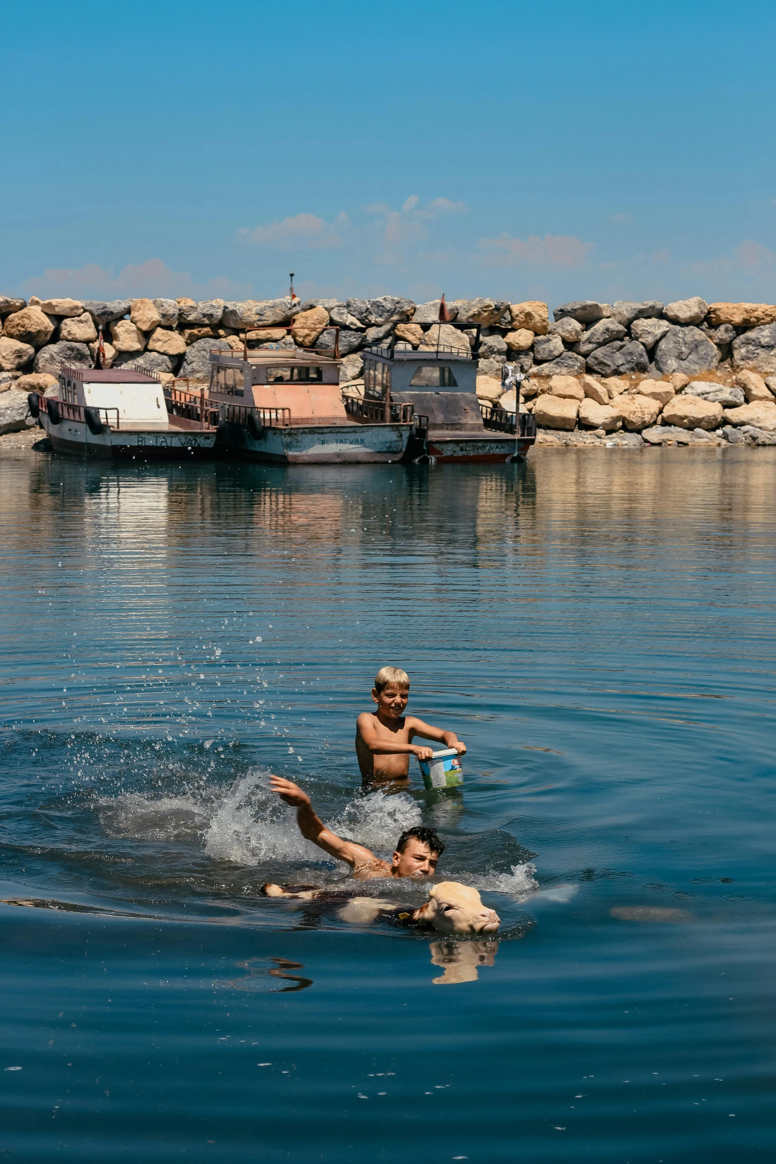 a couple of people swimming in a body of water, by Peter Churcher, mediterranean fisher village, enes dirig, near a jetty, iron smelting pits