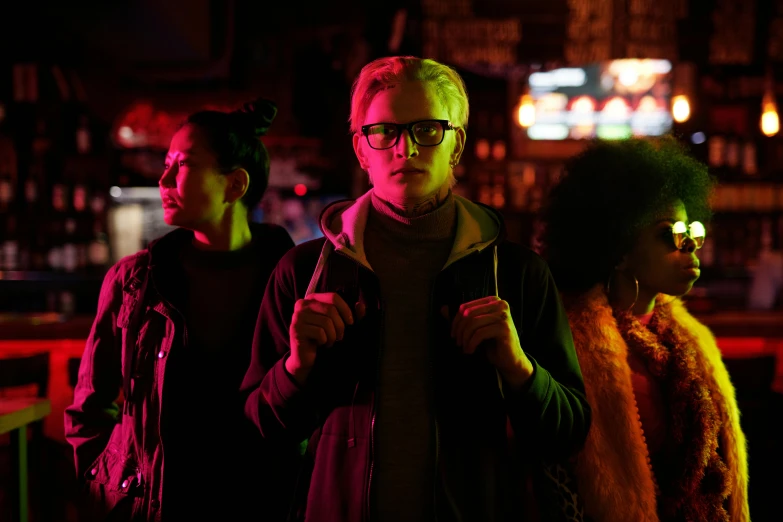 a group of people standing next to each other, by Nick Fudge, pexels, serial art, night clubs and neons, man with glasses, film promotional still, blonde man