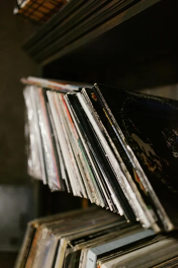 a stack of records sitting on top of a wooden shelf, unsplash, hans zimmer soundtrack, high angle close up shot, multiple stories, black