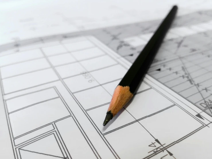 a pencil sitting on top of a piece of paper, a detailed drawing, building plans, looking towards the camera, medium: black pencil, looking partly to the left