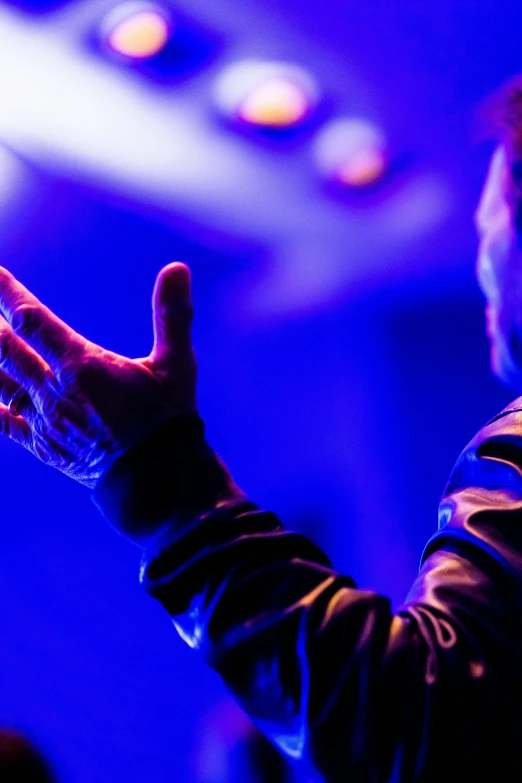 a man that is standing in front of a microphone, an album cover, by Dan Content, pexels, happening, prayer hands, blue and purple lighting, 15081959 21121991 01012000 4k, mike mignogna