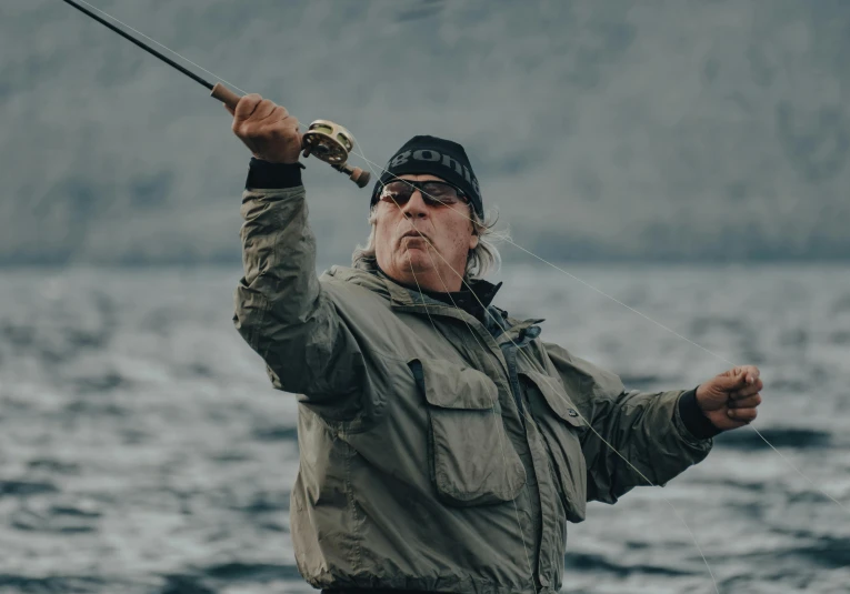 a man that is standing in the water with a fishing rod, ian callum, flying towards the camera, ready to eat, norwegian man