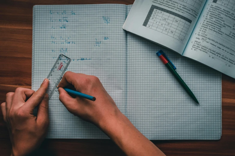 a person holding a ruler over a piece of paper, a photo, by Carey Morris, pexels, textbooks and books, square lines, фото девушка курит, blackboard in background