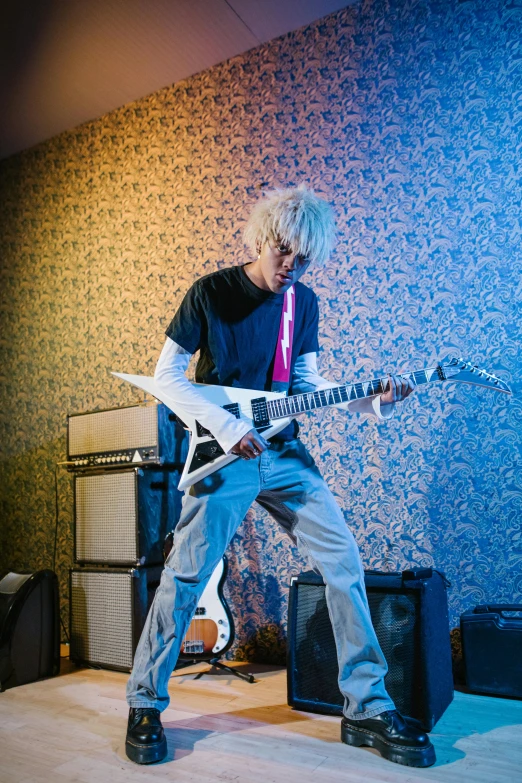 a man that is playing a guitar in a room, inspired by Tadanori Yokoo, platinum blonde, press photos, electrifying, teenage no