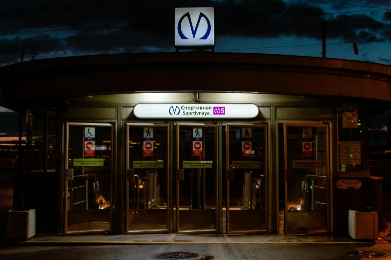 the entrance to a train station lit up at night, by Matt Cavotta, voge photo, r / vexilology, viral image, ad image