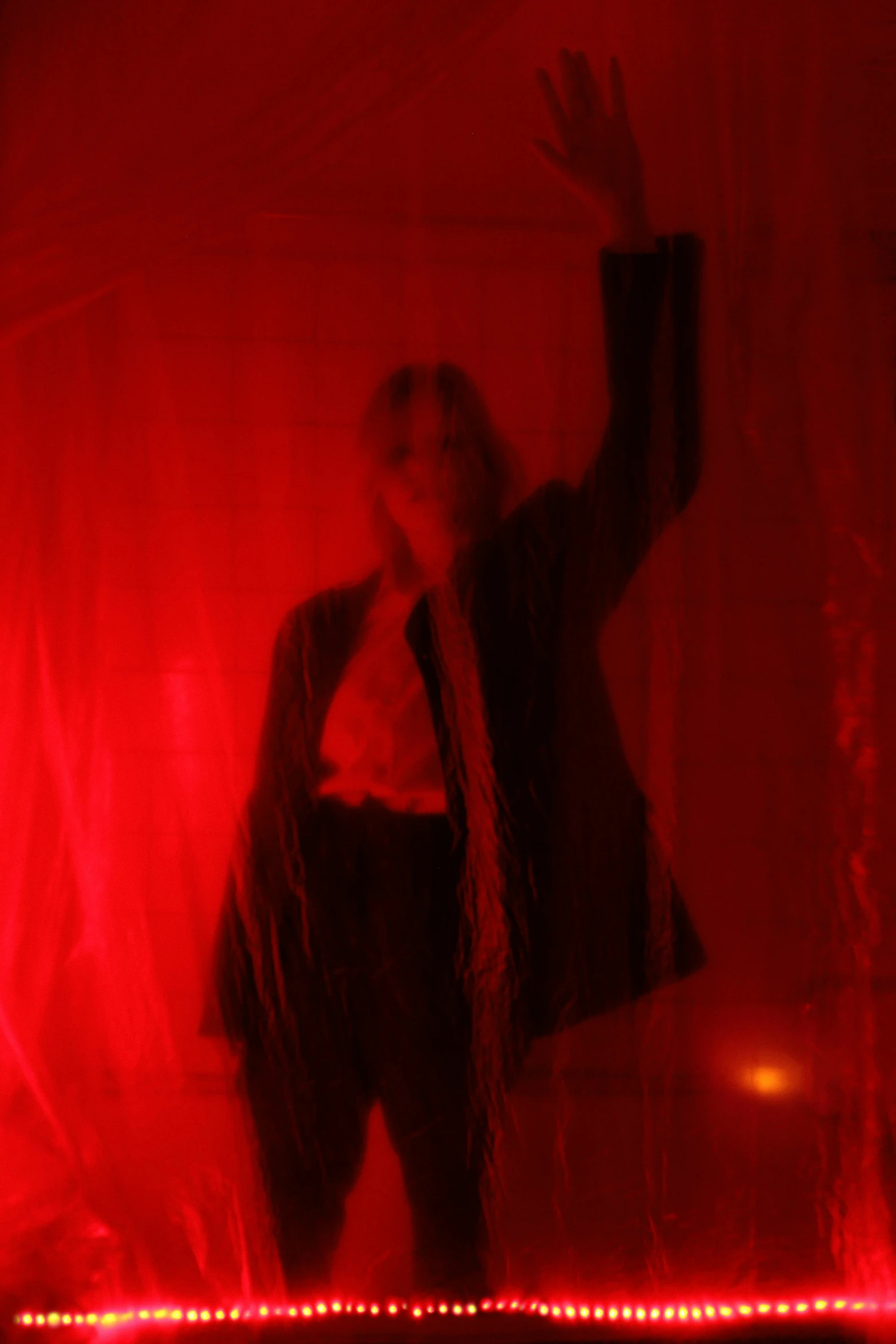 a man standing in front of a red light, red curtains, behind her is a scary atmosphere, triumphant pose, ritual occult gathering