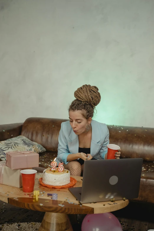 a woman sitting on a couch in front of a cake, trending on pexels, sitting at a computer, at a birthday party, ashteroth, sitting on a mocha-colored table