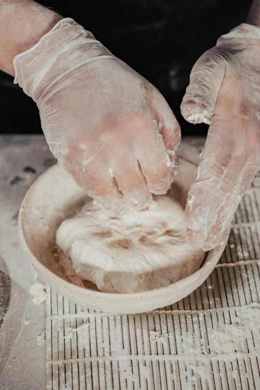 a person making dough in a bowl on a table, inspired by Sarah Lucas, process art, soap carving, finely textured, a dramatic, elbow gloves