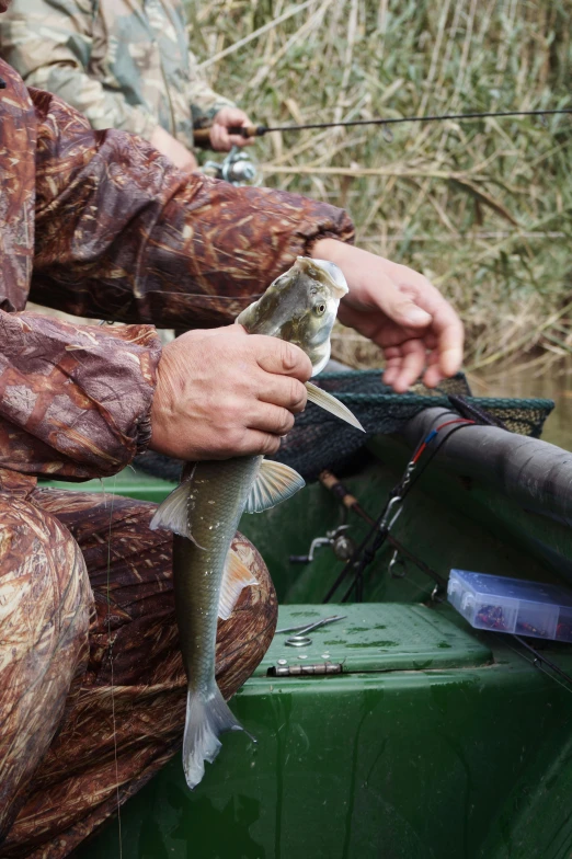 a man sitting in a boat holding a fish, bayou, zoomed in, uploaded, los carpinteros