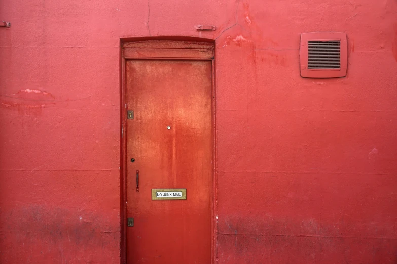 a red building with a fire hydrant in front of it, by Elsa Bleda, pexels contest winner, postminimalism, wood door, hidden message, iain mccaig, helio oiticica