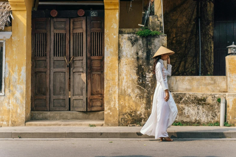 a woman walking down the street with a hat on, inspired by Ruth Jên, pexels contest winner, happening, vietnamese temple scene, ancient white dress, leaning on door, hakama kimono