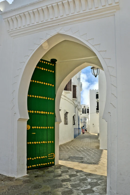 an archway leading to a white building with a green door, arabesque, white houses, green and gold, tuareg, looking down street