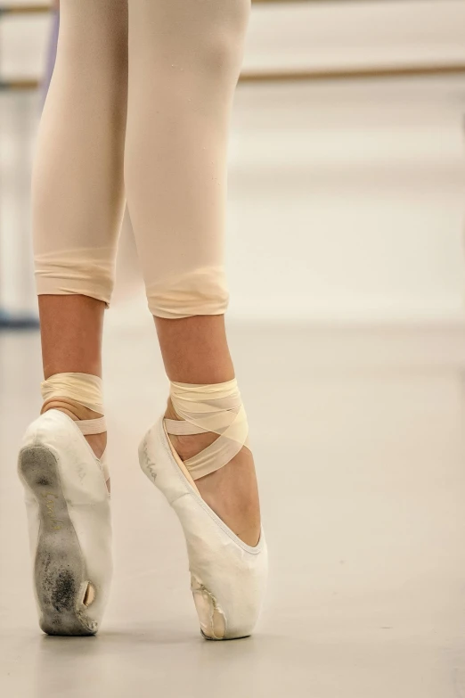 a close up of a person's feet in ballet shoes, arabesque, breeches, cream, standing in class, amanda lilleston