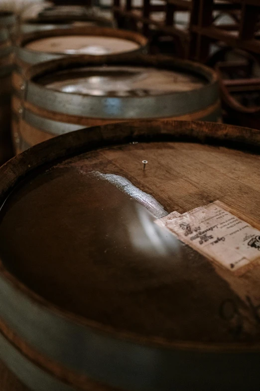 a bunch of barrels sitting next to each other, a portrait, unsplash, process art, labels, close-up shot taken from behind, old fashioned, in liquid