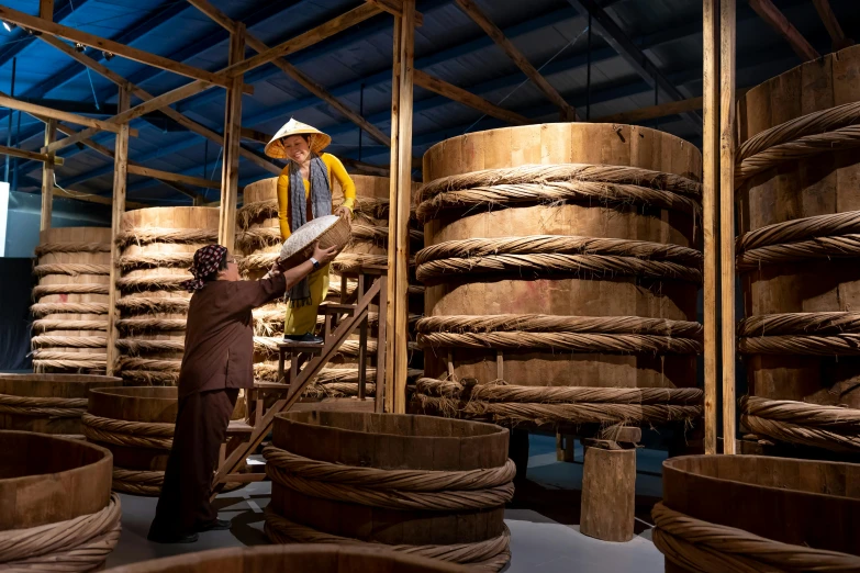 a couple of men that are standing in a room, inspired by Li Di, wooden crates and barrels, bao phan, museum lighting, wearing huge straw hat