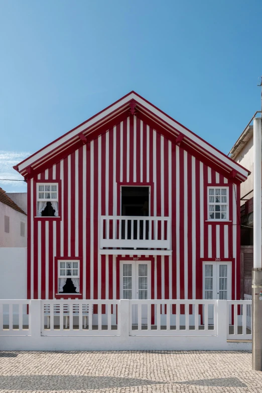 a red and white house with a white fence, inspired by Fernando Gerassi, pexels contest winner, op art, arrendajo in avila pinewood, red facial stripe, seaside victorian building, elevation view