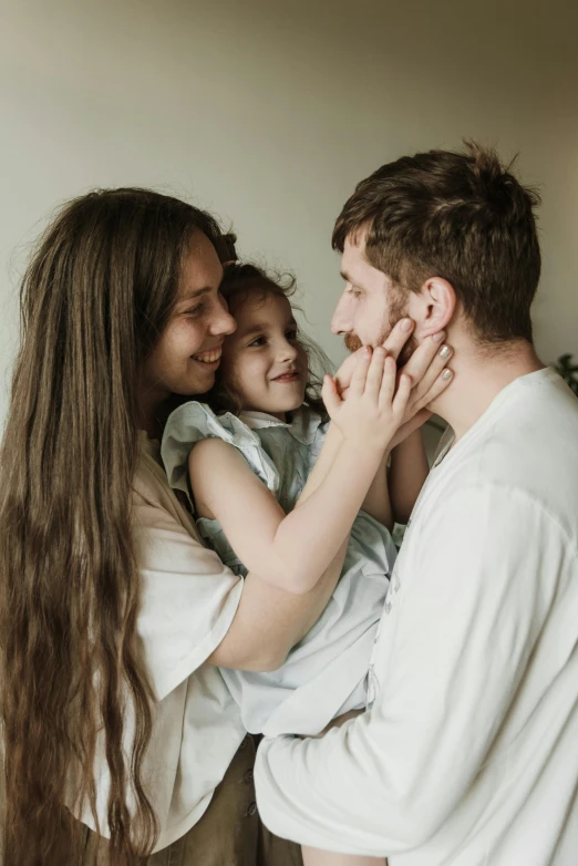 a man holding a little girl in his arms, pexels contest winner, husband wife and son, looking at each other mindlessly, brunette, portrait of family of three