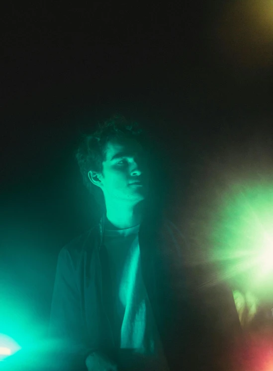 a man that is standing in the dark, an album cover, pexels, blue and green light, loish |, complementary lighting, underexposed grey