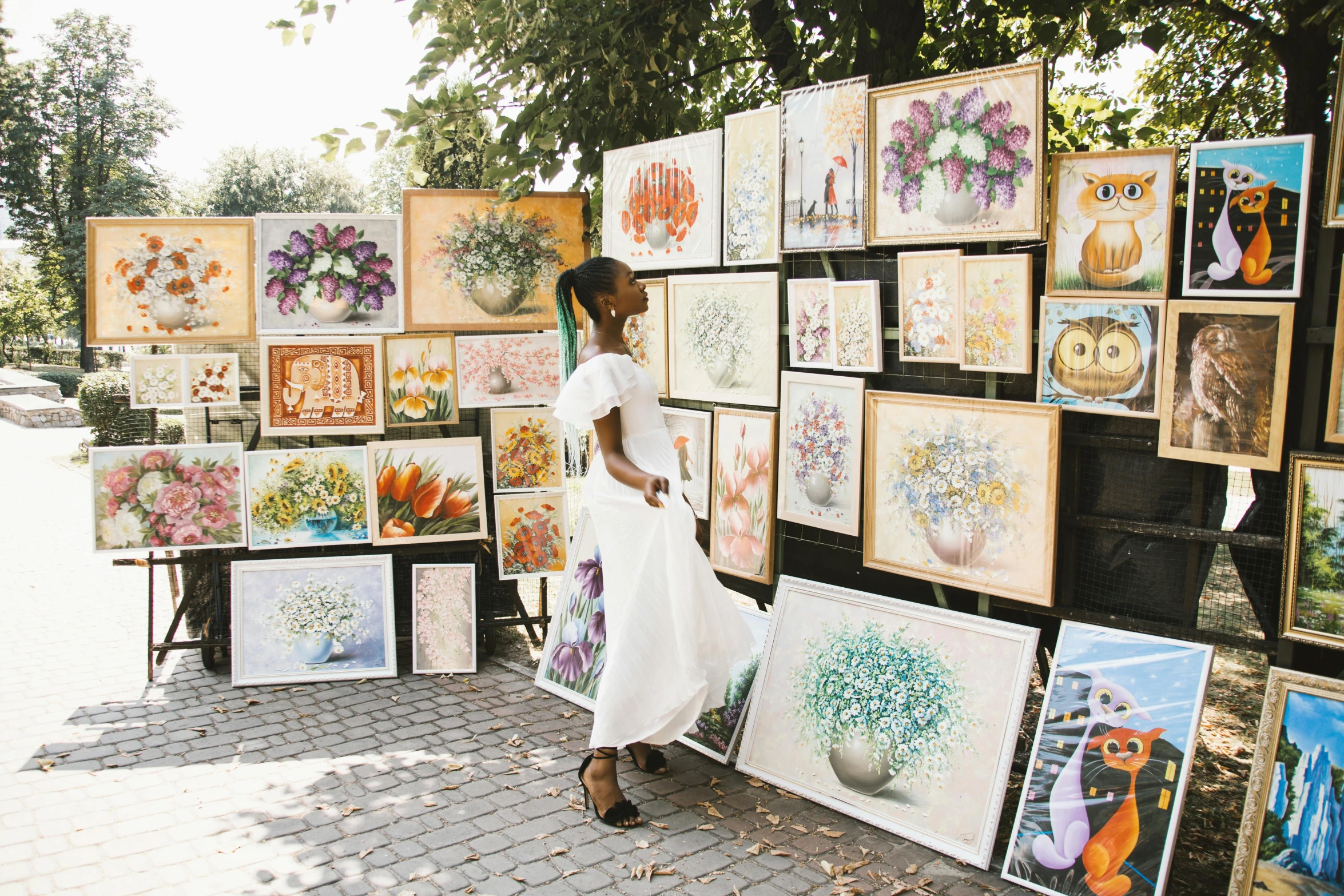 a woman standing in front of a wall of paintings, a watercolor painting, by karolis strautniekas, pexels contest winner, visual art, street vendors, al fresco, 15081959 21121991 01012000 4k, african arts