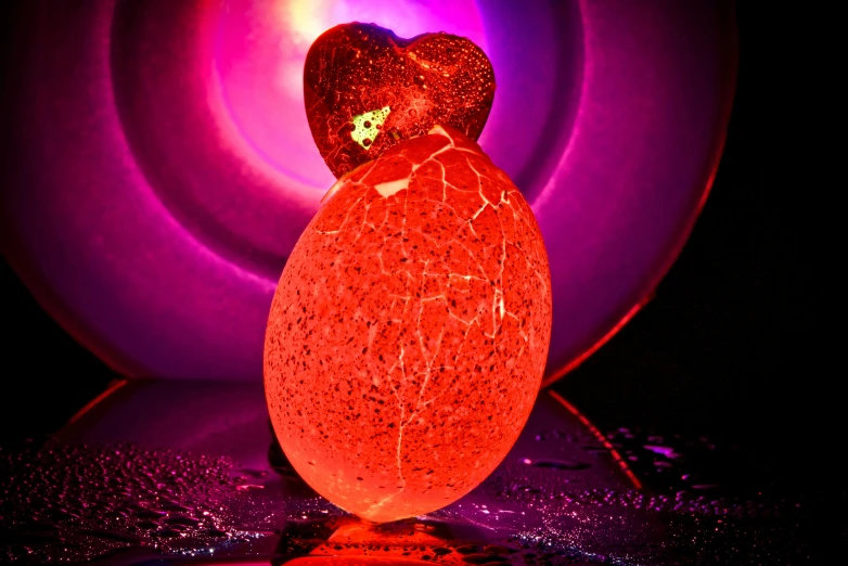 a heart shaped candle sitting on top of a table, an abstract sculpture, inspired by Doug Ohlson, art photography, dragon eggs, orange and red lighting, translucent eggs, neon light showing injuries