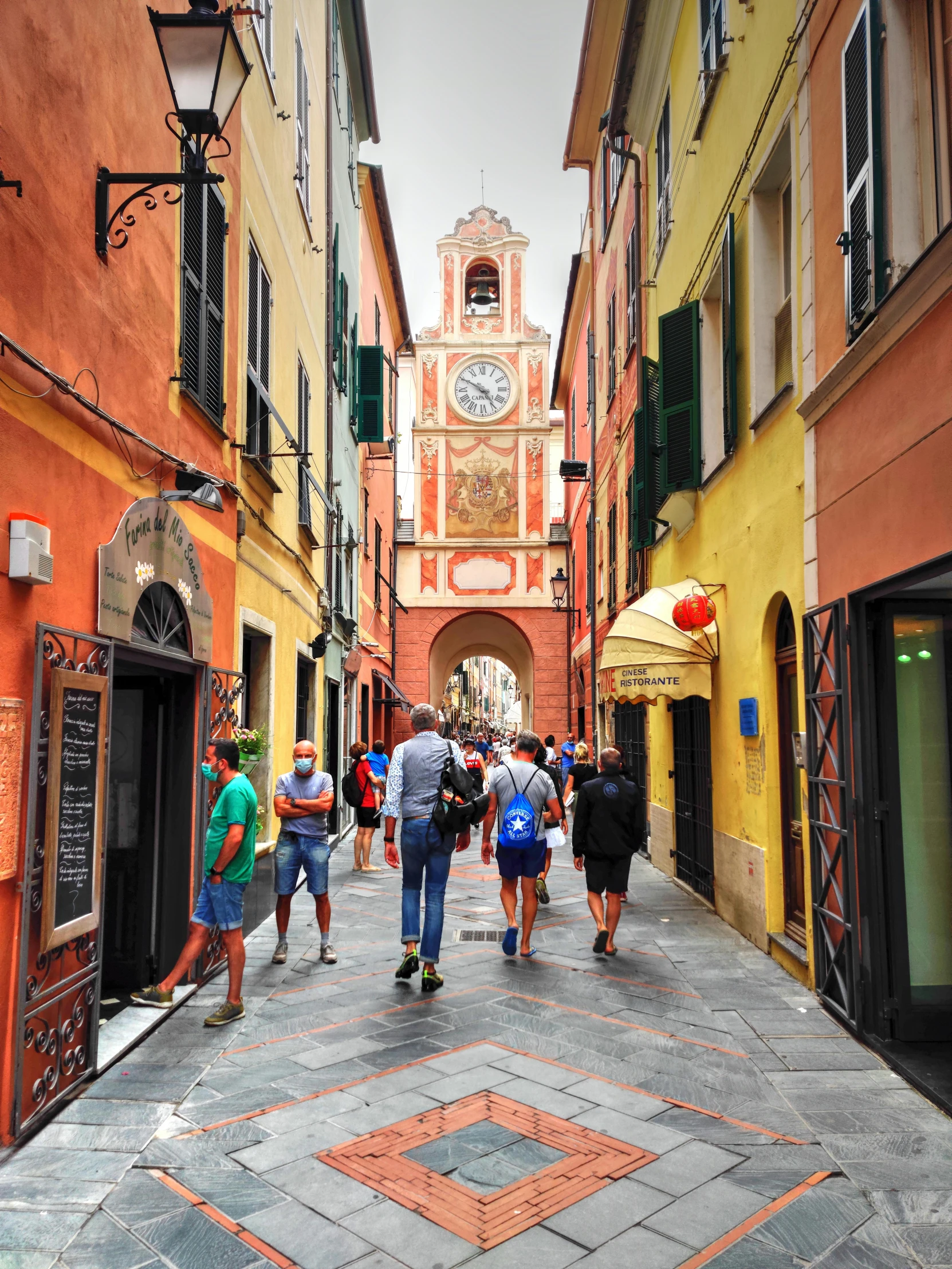 a group of people walking down a narrow street, pexels contest winner, renaissance, red - yellow - blue building, clock tower, italian beach scene, color photo