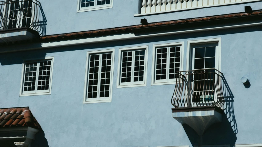 a blue building with a balcony and balconies, inspired by Canaletto, pexels contest winner, neoclassicism, sunny bay window, blue gray, minimalist photorealist, light-blue