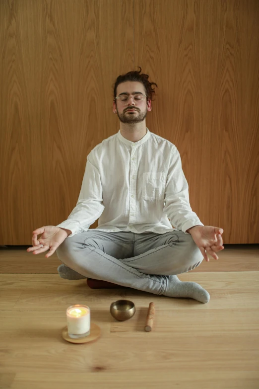 a man sitting on the floor in front of a candle, meditation pose, owen gent, profile image, confident looking