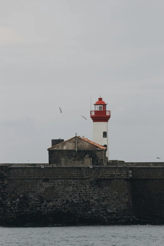 a red and white lighthouse in the middle of a body of water, farol da barra, grey sky, 1 4 8 0 s, square