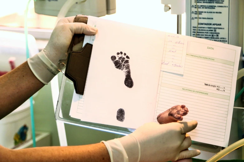 a close up of a person holding a folder, by Alison Watt, private press, footprints, medical lab, calf, brown