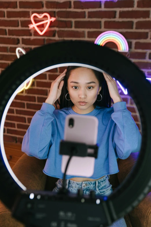 a woman taking a picture of herself in a mirror, trending on pexels, symmetrical neon rim light, young asian girl, blue rim lighting, sitting down