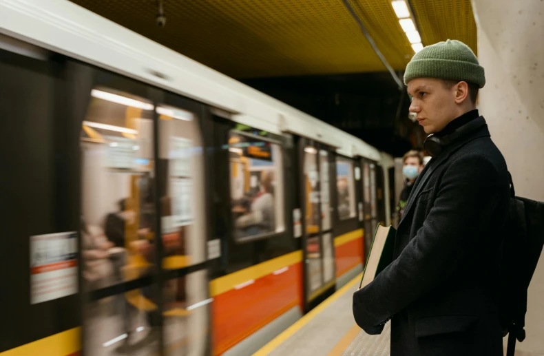 a man waiting for a train at a subway station, by Emma Andijewska, pexels contest winner, happening, greta thunberg, carrying a tray, thumbnail, looking in front